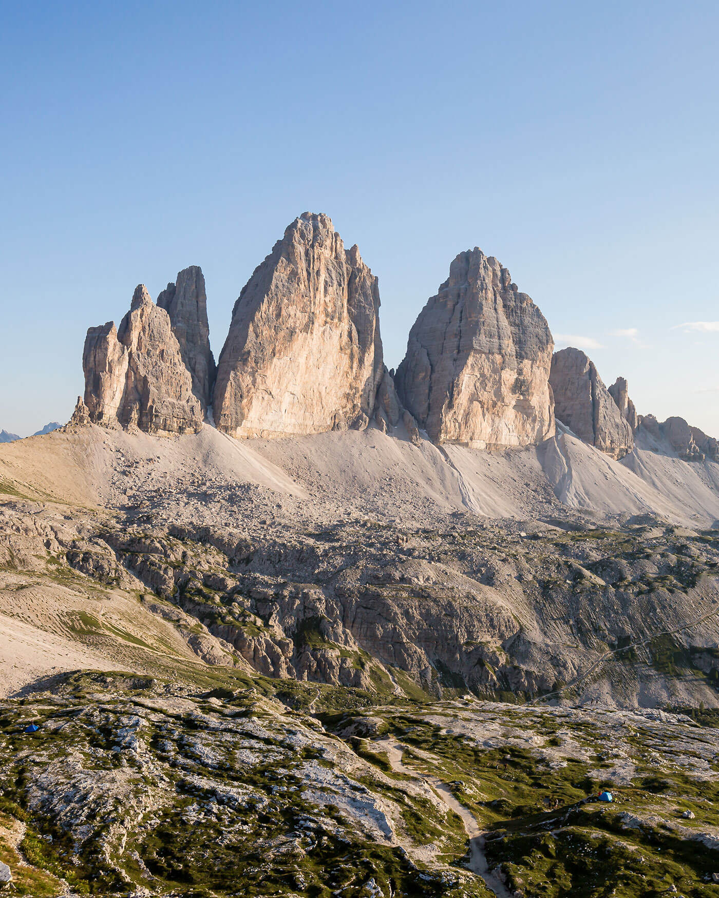 Felsige Berggipfel unter einem klaren blauen Himmel, mit zerklüftetem Gelände und spärlichem Grün im Vordergrund. - Ansitz Toldt Dolomites Village