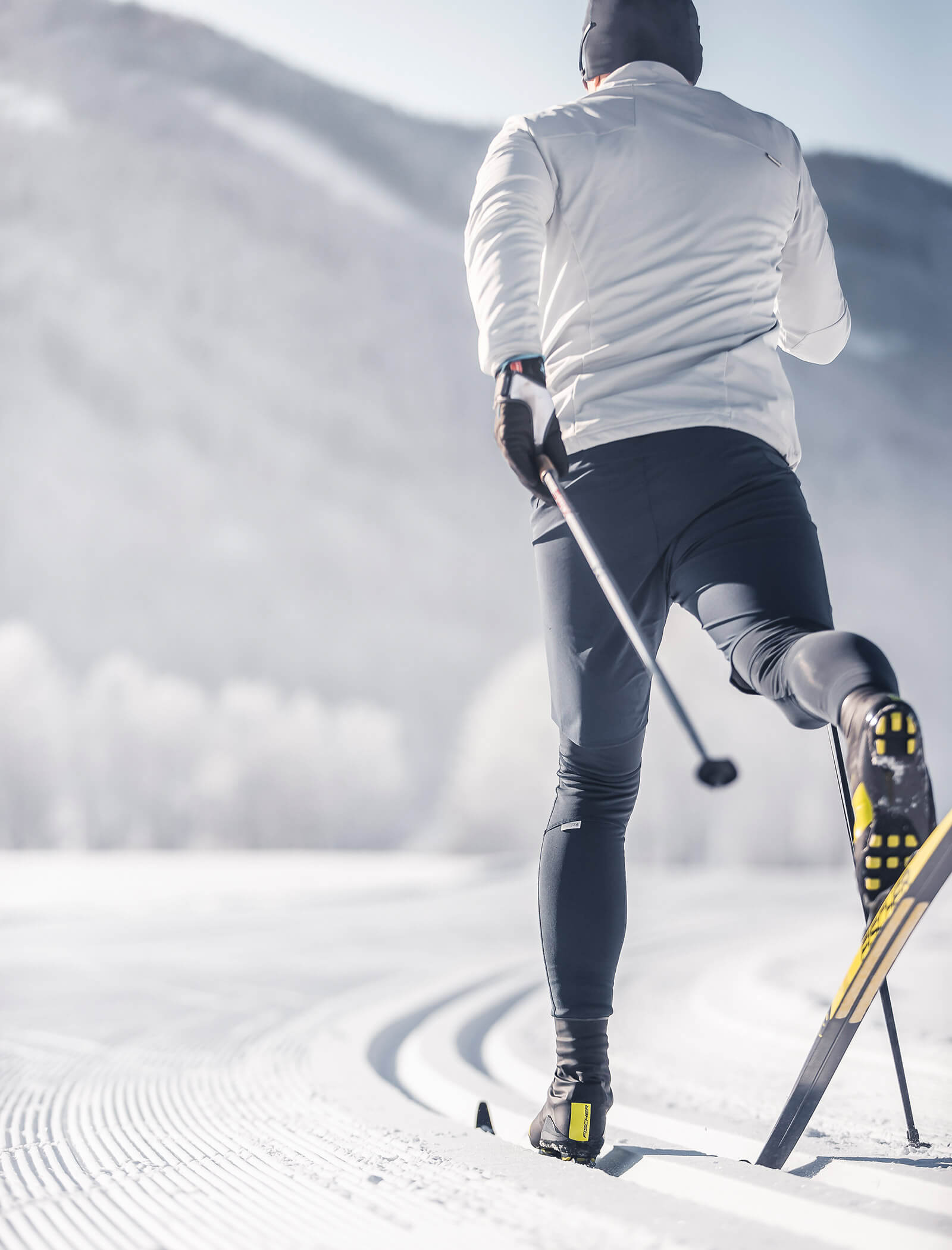 Person beim Skilanglauf auf einer verschneiten Loipe mit schneebedeckten Bergen im Hintergrund. - Ansitz Toldt Dolomites Village