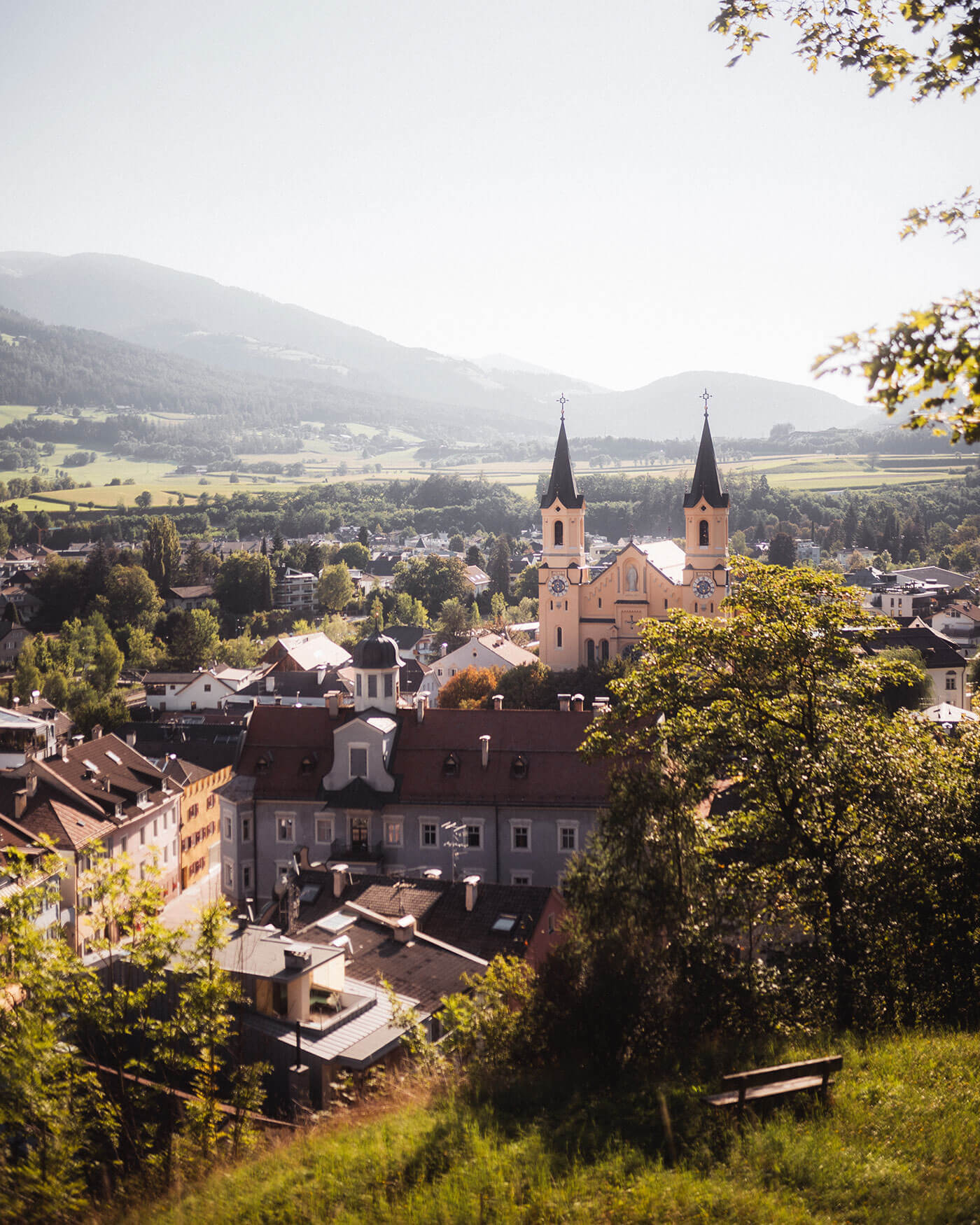 Ein malerischer Blick auf eine kleine Stadt mit einer Kirche, Bergen und üppigem Grün unter einem klaren Himmel. - Ansitz Toldt Dolomites Village