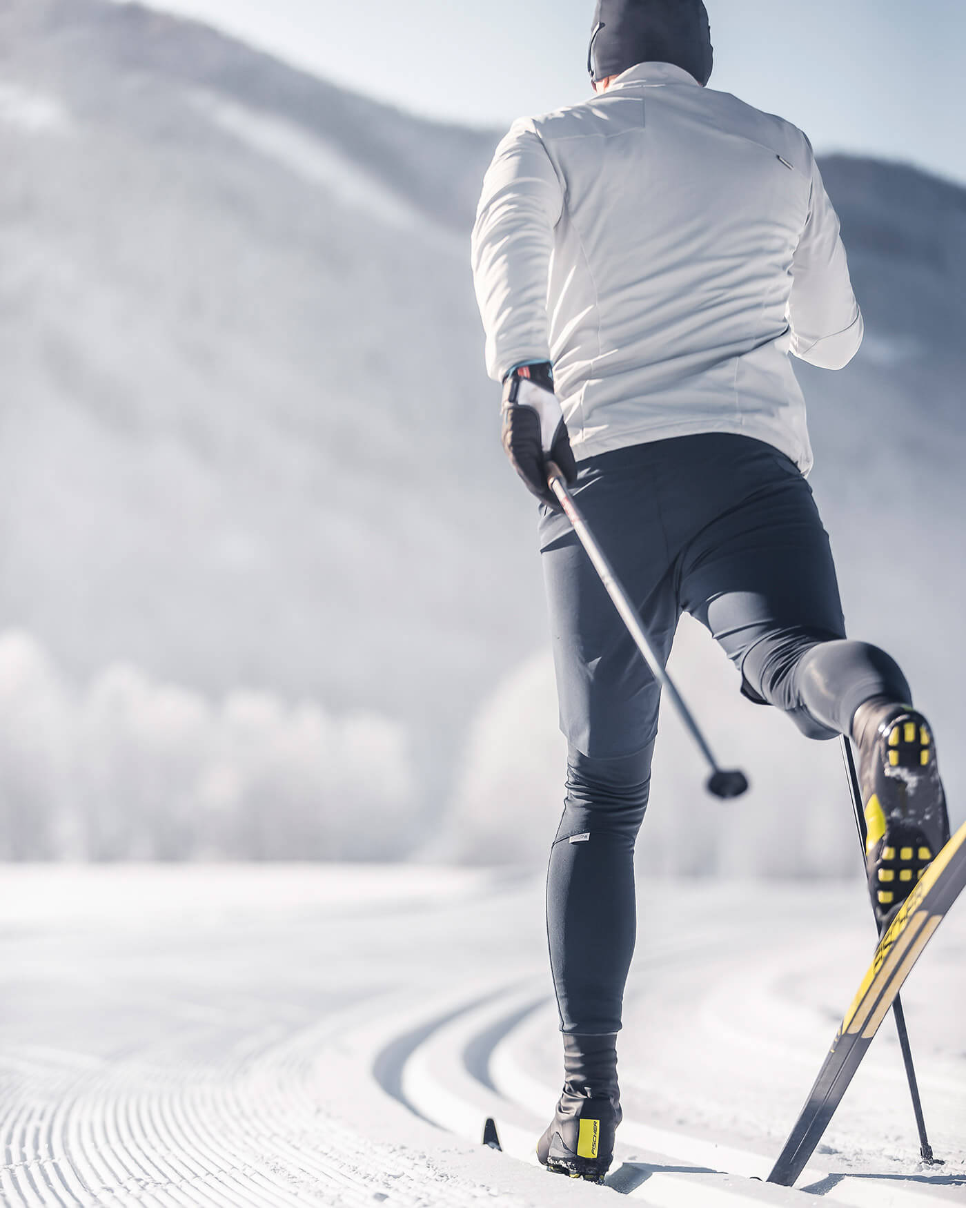 Person beim Skilanglauf auf einer präparierten, verschneiten Loipe mit Bergen im Hintergrund. - Ansitz Toldt Dolomites Village